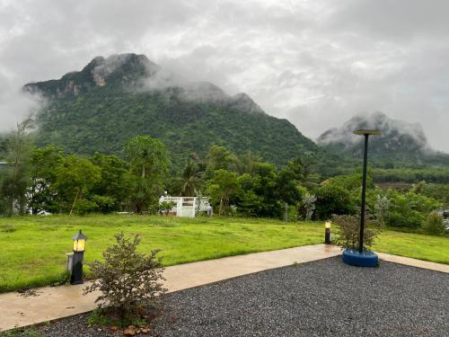 a field with a mountain in the background with a street light at พิงภู ไทรโยค in Ban Lum Sum (1)