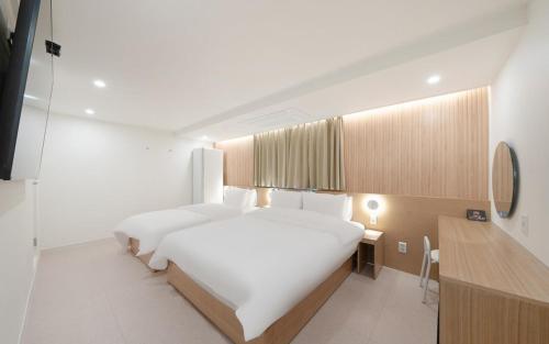 a bedroom with a large white bed and a desk at MH Hotel 3 - Junghwasan in Jeonju