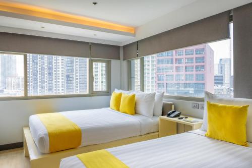 two beds in a hotel room with two windows at The Mini Suites Eton Tower Makati in Manila