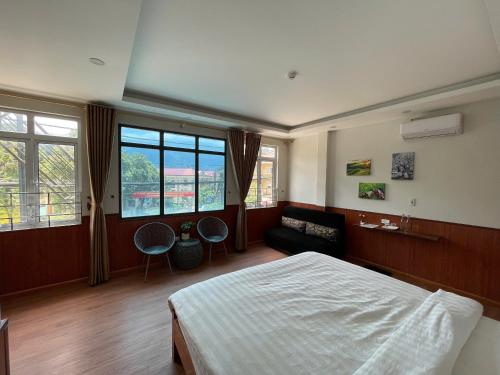 a bedroom with a bed and a couch and windows at Flaco Hostel and Booking Office in Sapa