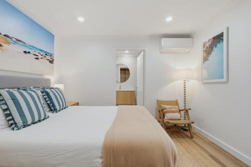 a white bedroom with a bed and a chair at Ralph Escapes Yallingup in Yallingup