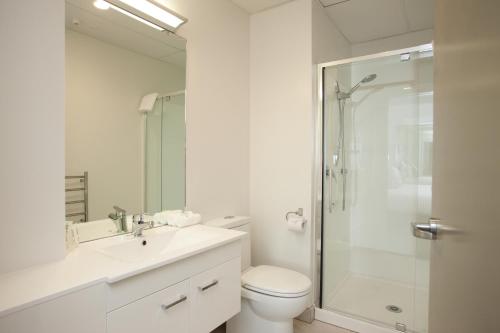 a white bathroom with a shower and a toilet at Quest Rotorua Central in Rotorua