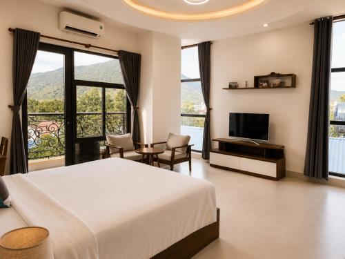 a bedroom with a bed and a tv and windows at Nam Hai Con Dao Hotel in Con Dao