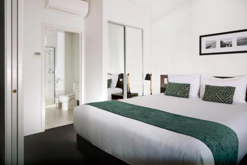 a bedroom with a large white bed and a bathroom at Quest Rotorua Central in Rotorua