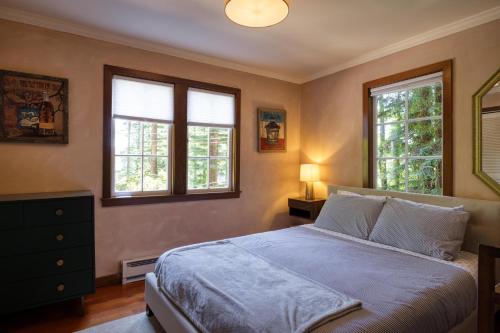 a bedroom with a bed and two windows at Wanderwood in Guerneville