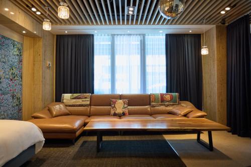 a brown leather couch in a room with a bed at Acube Hotel Dongdaemun in Seoul