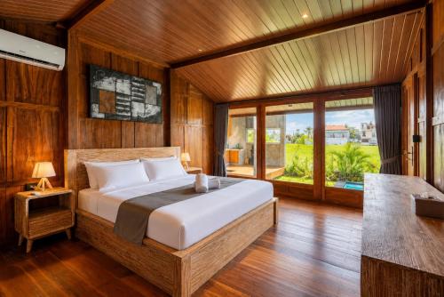 a bedroom with a bed and a large window at De Sirame Villa in Ubud