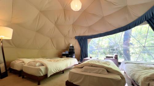 two beds in a room with a large window at glampark Otaru Hanaemi Hokkaido in Otaru