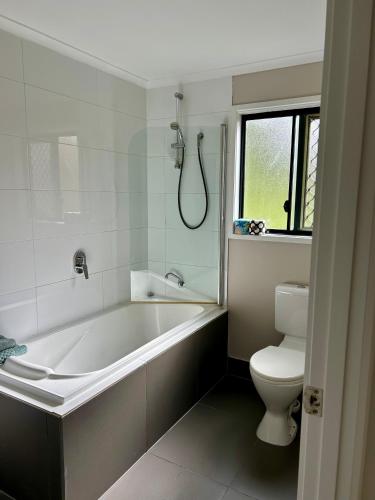 a white bathroom with a tub and a toilet at Hinterland Ocean Vista Escape in Maroochy River