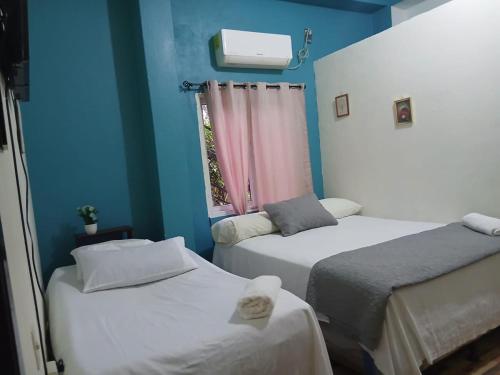 two beds in a room with blue walls and a window at Casa Miramar Tx in Trujillo