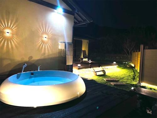a bathroom with a bath tub in the yard at night at 四季の庵 糸島 1300m2 大自然のパノラマ露天風呂 駐車場5台以上 サウナ 専用BBQ施設 ペット可 in Itoshima