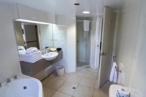 a bathroom with a sink and a shower and a toilet at Ocean International Hotel in Mackay