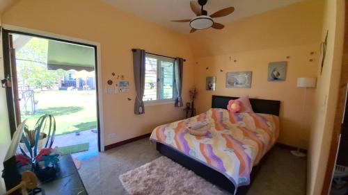 a bedroom with a bed and a ceiling fan at บ้านน้ำผึ้งโฮมสเตย์ Pool & Garden in Suan Phung