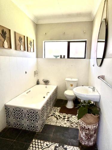 a bathroom with a tub and a toilet and a sink at SPAat343 in Roodeplaat