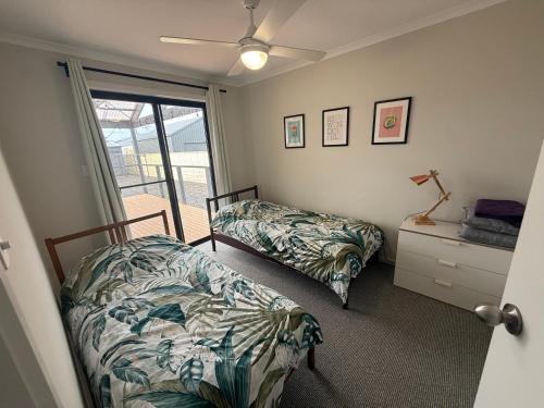 a bedroom with two beds and a door to a balcony at Parsee Escape in Edithburgh