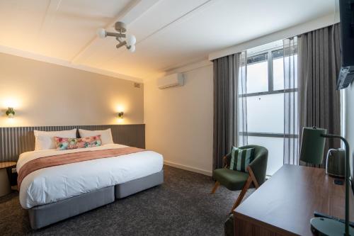 a hotel room with a bed and a desk and a window at Doonside Hotel, Blacktown in Doonside