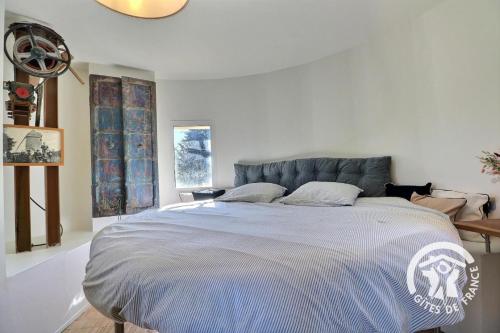 a white bedroom with a large bed in it at Le moulin de la chicane in Orgères