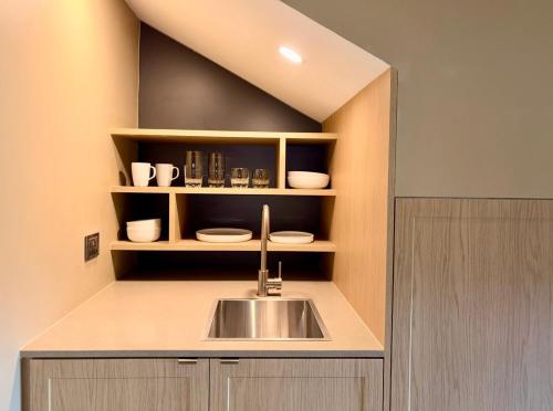 a kitchen with a sink and a shelf with dishes at Mt Buller Chalet Hotel & Suites in Mount Buller