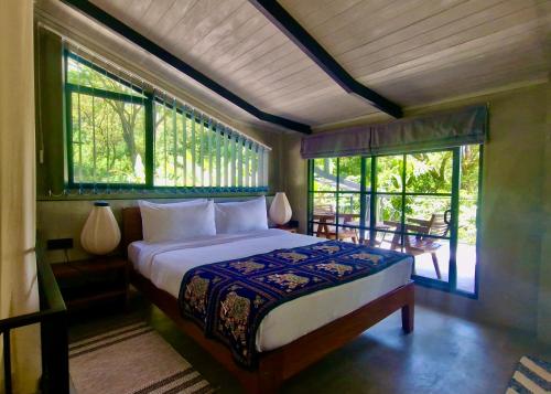 a bedroom with a bed in a room with windows at GlenMyu Estate in Haputale