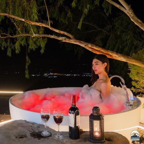 a woman in a bath tub with wine glasses at Paradiso Khaokho By N in Ban Huai Phai