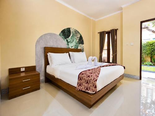 a bedroom with a large bed with a wooden headboard at Eslem GuestHouse in Canggu