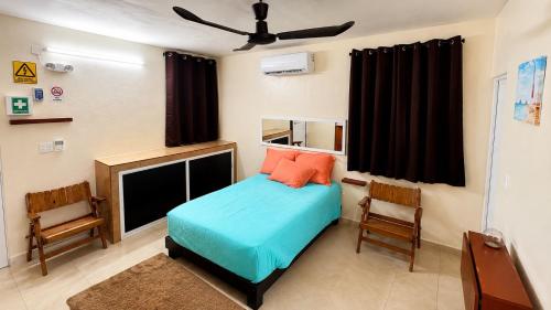 a bedroom with a bed and two chairs and a tv at Casa paz in Isla Mujeres