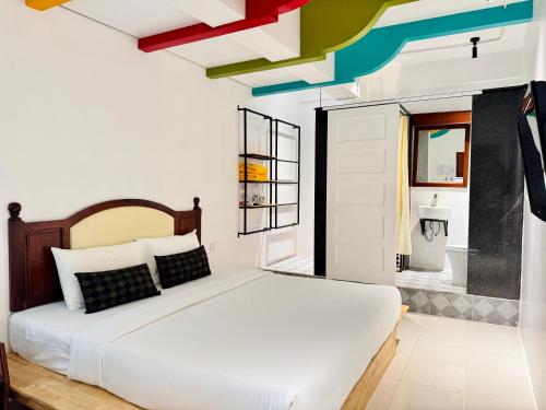 ein Schlafzimmer mit einem weißen Bett und farbenfrohen Decken in der Unterkunft ActivateC3 Hostel in Phnom Penh