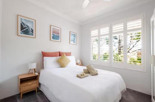 a white bedroom with a bed and a window at Lovley sunlit apartment walking distance to Cronulla mall and Cronulla Beach in Cronulla