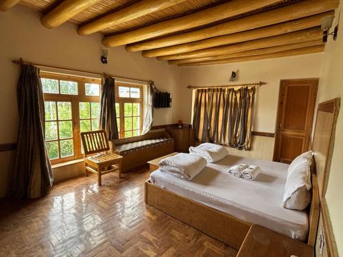 a bedroom with a bed and a couch and windows at Gangs-Shun Homestay in Leh