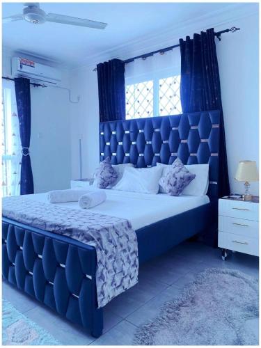 a blue bedroom with a large bed with a blue headboard at Nyali Glam Apartment in Mombasa