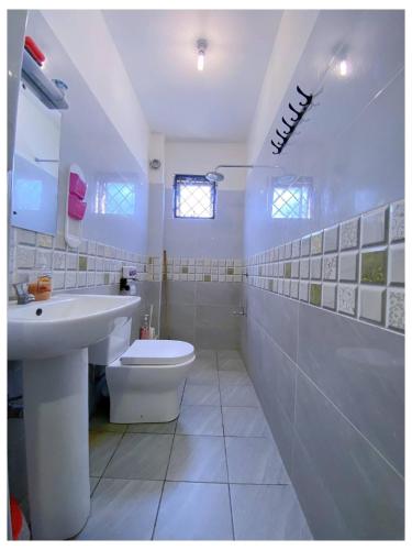 a white bathroom with a sink and a toilet at Nyali Glam Apartment in Mombasa