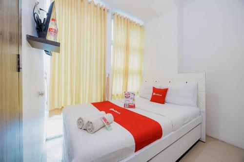 a small bedroom with a bed with red and white sheets at RedDoorz Near MRT Bendungan Hilir in Jakarta