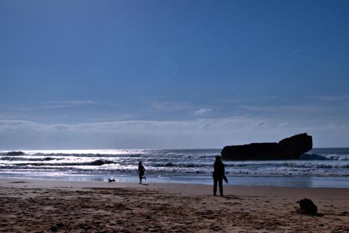 two people standing on a beach near the ocean at Tonel Apartamentos Turisticos in Sagres