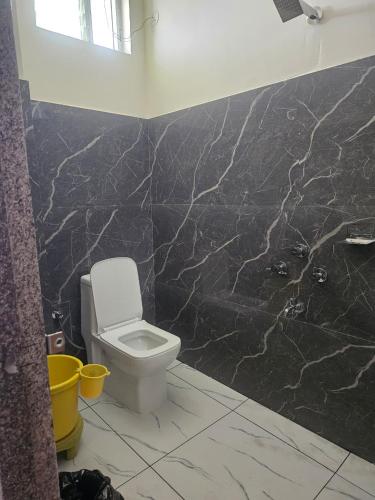 a bathroom with a toilet and a black marble wall at Hampi Rock-Inn in Hampi