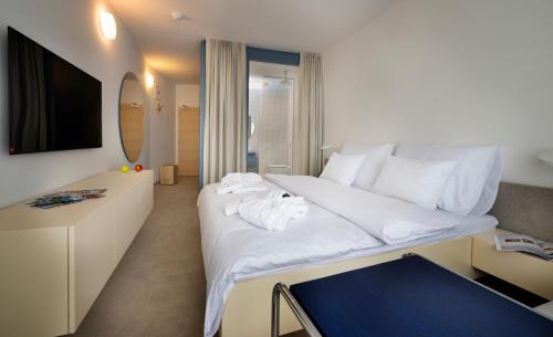 a bedroom with a large white bed and a mirror at Hotel SOREA MORAVA in Tatranská Lomnica
