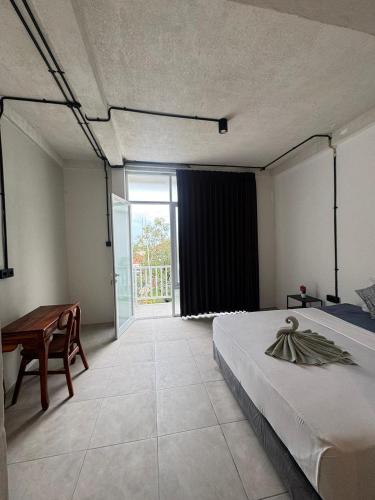 a bedroom with a bed and a desk and a window at Adi Bali Homestay in Uluwatu