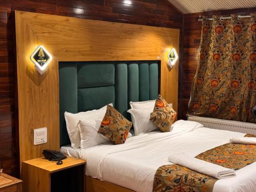 a bedroom with a large bed with a green headboard at The Cedar Pahalgam in Pahalgām