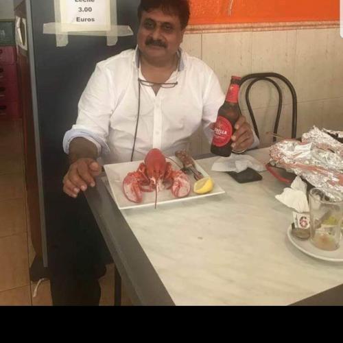 a man sitting at a table with a plate of food at Hotel Melodyinn in Gujrāt