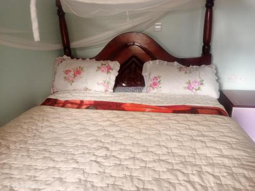 a bed with a wooden headboard and two pillows at WYCLIFF BnB in Chabahinga