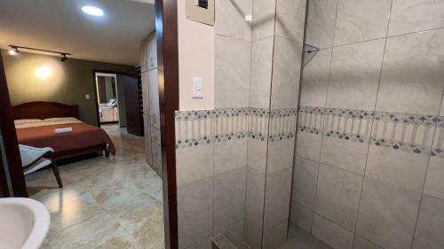 a bathroom with a shower and a sink and a bed at Spacious Suite privacy, and comfort in Riobamba