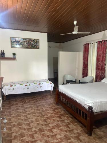 a bedroom with two beds and chairs and a ceiling at Hasiru Homestay in Mudigere