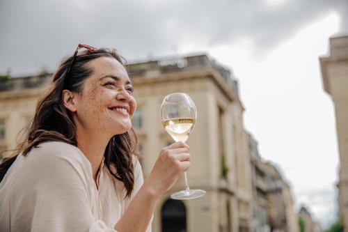 a woman holding up a glass of white wine at Hyatt Centric Reims in Reims
