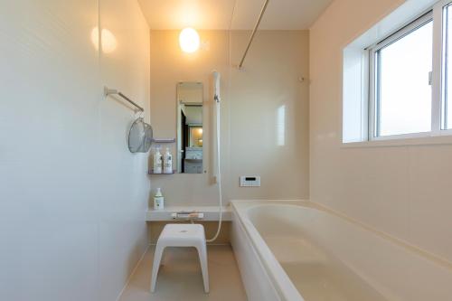 a white bathroom with a tub and a stool in it at NASU den-en in Nasu