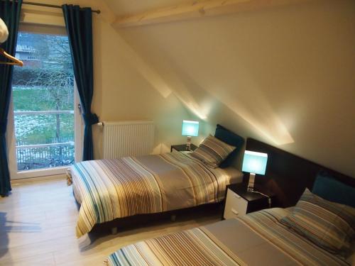 a bedroom with two beds and two lamps on tables at Archipel Holiday Cottage in Ellezelles
