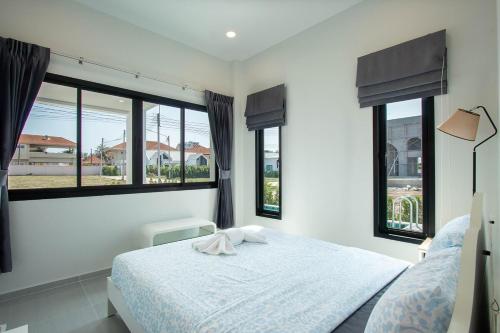 a bedroom with a white bed with windows at Pool Villa Maephim 4, by Somjai in Klaeng