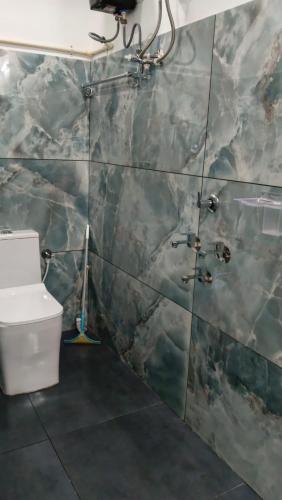 a bathroom with a toilet and a tiled wall at Tranquil Tents in Trivandrum