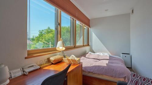a bedroom with a bed and a desk with a window at Shinwaso Kaishin in Amakusa