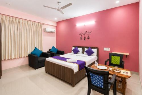 a bedroom with a bed and a table and chairs at Hotel Golden Suites in Bangalore