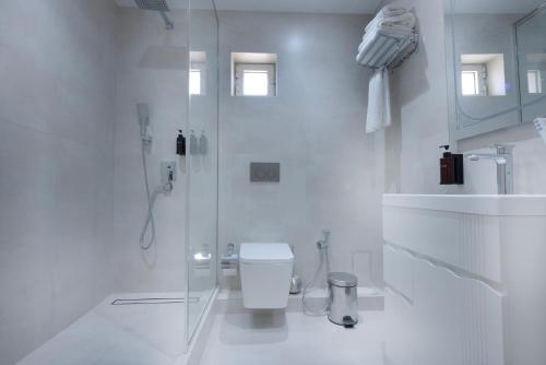 a white bathroom with a toilet and a shower at Ismat Premium Guest House in Bukhara