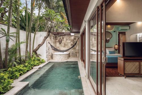 a pool in the middle of a house with a bathtub at Aksari Villa Seminyak by Ini Vie Hospitality in Seminyak